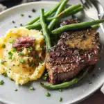 Classic steak au poivre (French pepper steak) with mashed potatoes and green bean bundles