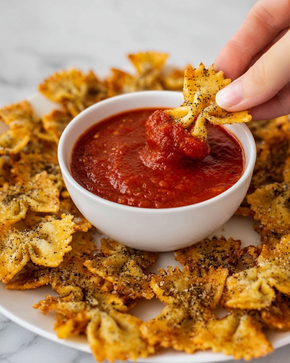 A white bowl filled with thick red tomato sauce is placed in the center of a white plate, covered with many small, golden-brown crispy snacks shaped like bow ties, sprinkled with black pepper. A woman's hand holds one of the snacks dipped halfway into the sauce, highlighting the sauce's smooth and chunky texture. The scene is set on a white marbled surface, showing a close-up view with soft lighting. photo taken with an iphone --ar 4:5 --v 7