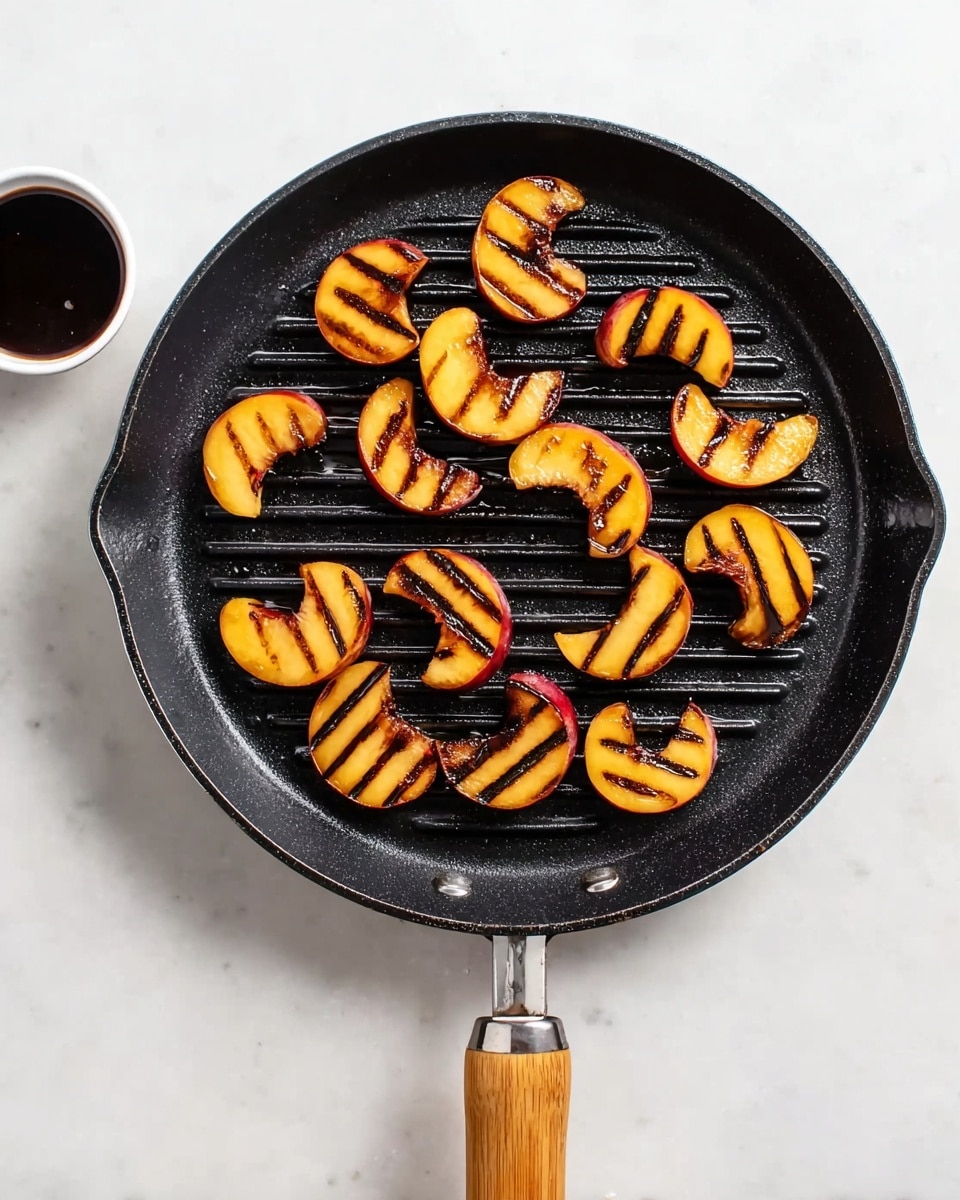 A black round grill pan with a wooden handle holds fifteen peach slices arranged in a scattered pattern, each slice showing clear dark brown grill marks on golden-yellow and reddish-peach skin. The pan sits on a white marbled surface. To the upper left of the pan, there is a small white bowl filled with thick dark syrup. The scene is bright and clean, with a simple, fresh look. Photo taken with an iphone --ar 4:5 --v 7