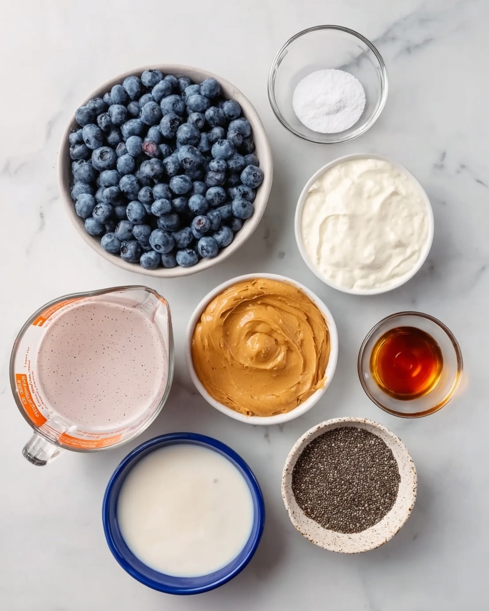 The image shows a group of ingredients placed on a white marbled surface arranged in a loose circle. There is a large clear glass measuring cup filled with a light pink liquid at the bottom left. Next to it on the right, a white bowl with a blue rim holds thick white yogurt. Below the yogurt bowl is another white bowl with a blue rim filled with smooth light brown peanut butter. Above the yogurt to the right is a small clear glass bowl holding white salt. Above this is a small clear glass cup with dark amber vanilla extract. Towards the top right sits a round white bowl with a speckled texture, full of tiny black chia seeds. To the left of the chia bowl, a deep white bowl holds many plump blueberries, dark blue with a slight frosty look. Above the blueberries is a small white bowl with orange trim holding amber liquid maple syrup. Between the chia bowl and the yogurt bowl, there is a small white bowl with orange trim containing a beige round yeast disk. photo taken with an iphone --ar 4:5 --v 7