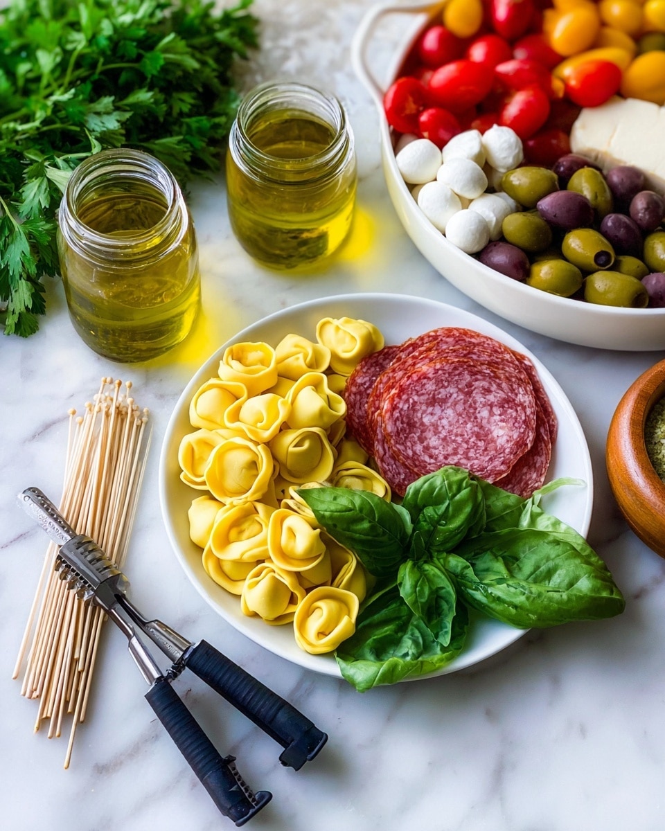 A white plate holds three main layers arranged side by side: bright yellow tortellini pasta on the left with a smooth, slightly curled texture, a half slice of red and white speckled salami in the middle with a rough texture, and fresh green basil leaves on the right with visible veins and a shiny surface. Behind the plate, there is a white bowl filled with colorful items: red cherry tomatoes, green olives, dark purple olives, and small white mozzarella balls, all with a smooth and glossy appearance. On the white marbled surface around the plate, there are two glass jars with light golden olive oil, one jar slightly taller than the other, a small wooden bowl holding a honey dipper, and some fresh green leafy parsley on the left side. In the foreground, black-handled garlic press with crushed garlic inside is positioned near a small bunch of wooden toothpicks. Photo taken with an iphone --ar 4:5 --v 7