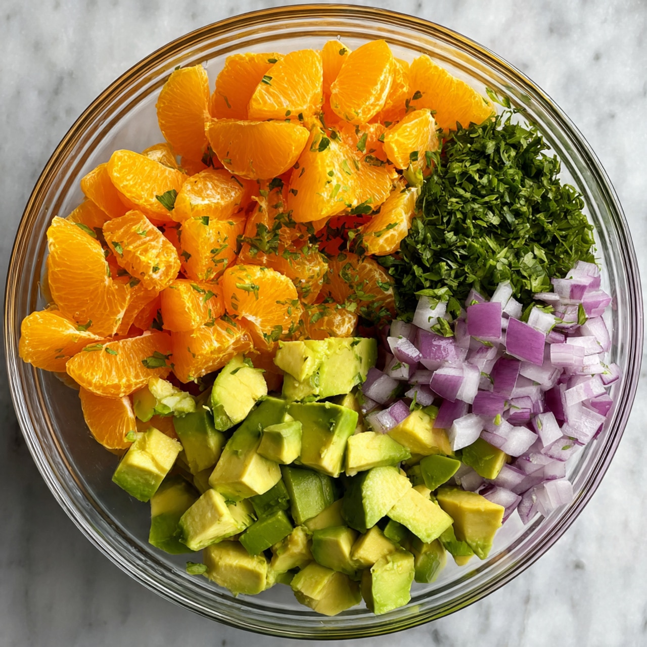 A white bowl holds five sections of chopped ingredients, each neatly placed next to each other. On the bottom left is bright orange pieces of mandarin, while the bottom center has small diced purple and white onion. To the bottom right and upper right are two shades of green; the first is light green avocado cubes, and the second is a darker green, also avocado cubes. The top center shows finely chopped dark green parsley, and to its left are finely chopped green herbs or peppers. The bowl sits on a white marbled surface. Photo taken with an iphone --ar 4:5 --v 7