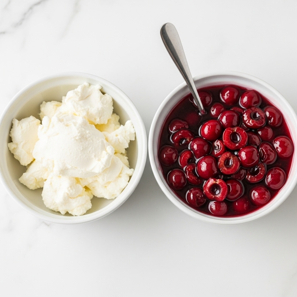 The image shows two white bowls on a white marbled surface. The bowl on the left is filled with smooth, creamy white cream cheese, with visible scoops taken out, showing its thick texture. The bowl on the right contains bright red cherry pie filling with whole cherries in a shiny, thick syrup, and a silver spoon rests inside the bowl, partially submerged in the filling. Photo taken with an iphone --ar 4:5 --v 7