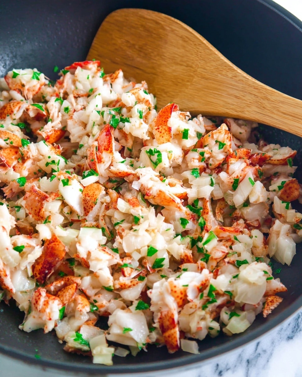 A close-up view of a pan filled with chopped cooked lobster meat mixed with small pieces of white onion and green parsley, showing a mix of white and orange colors from the lobster with green herbs scattered throughout. A wooden spoon is resting in the pan, with its smooth, light brown texture visible in the top right corner. The food looks fresh and lightly cooked, with small chunks and bits layered evenly. The background surface is a white marbled texture. photo taken with an iphone --ar 4:5 --v 7