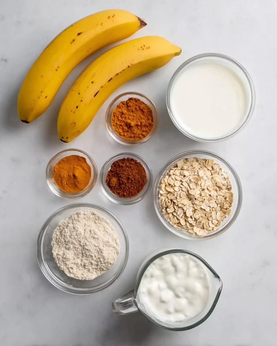 The image shows a top view of ingredients neatly arranged on a white marbled surface. In the top left corner, there are two whole yellow bananas with small brown spots. To the right and below are seven small clear glass bowls, each containing a different ingredient: bright orange turmeric powder, rich brown cinnamon powder, light brown powder (likely a spice or sweetener), dry light beige oats, thick white yogurt, bright white salt, and creamy white milk in a clear glass jug with a handle. The arrangement is clean and simple, with natural colors standing out against the white marbled background. Photo taken with an iphone --ar 4:5 --v 7