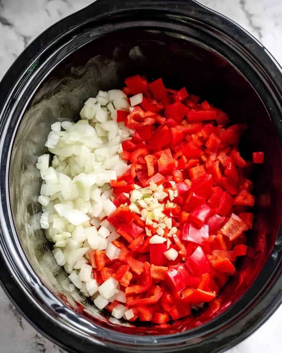 Inside a black slow cooker, there are two main layers of chopped vegetables. On the left side, there is a pile of off-white chopped onions with a slightly translucent texture. On the right side, there is a heap of bright red chopped bell peppers with small bits of minced garlic on top, giving a fresh and colorful contrast. The slow cooker has a shiny black interior, and the whole scene rests on a white marbled surface. photo taken with an iphone --ar 4:5 --v 7