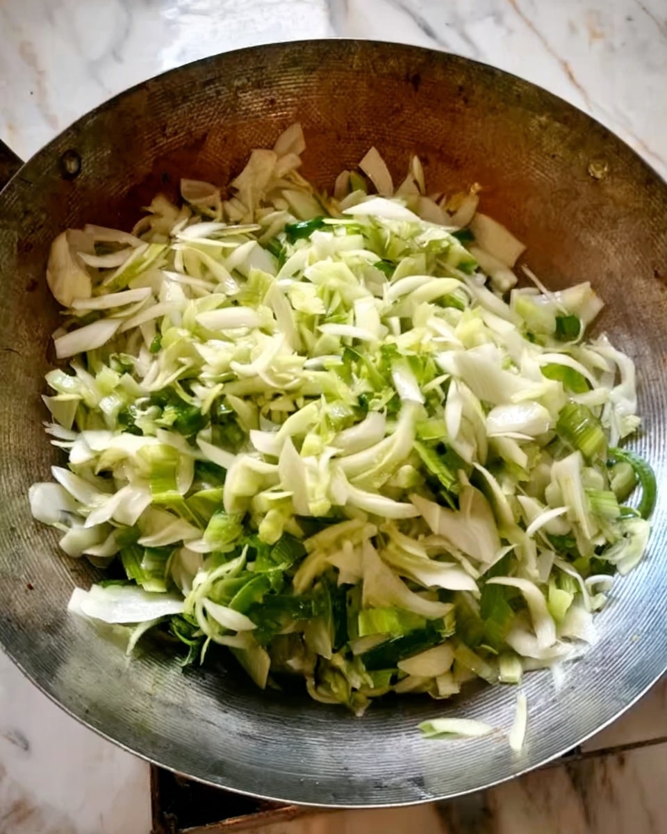 The image shows a large metal wok filled with chopped vegetables. The vegetables are mainly white and light green, with crisp, smooth textures, layered loosely and spread evenly across the wok. The wok has a slightly worn metallic surface with a shiny, reflective look, positioned on a white marbled surface. Photo taken with an iphone --ar 4:5 --v 7