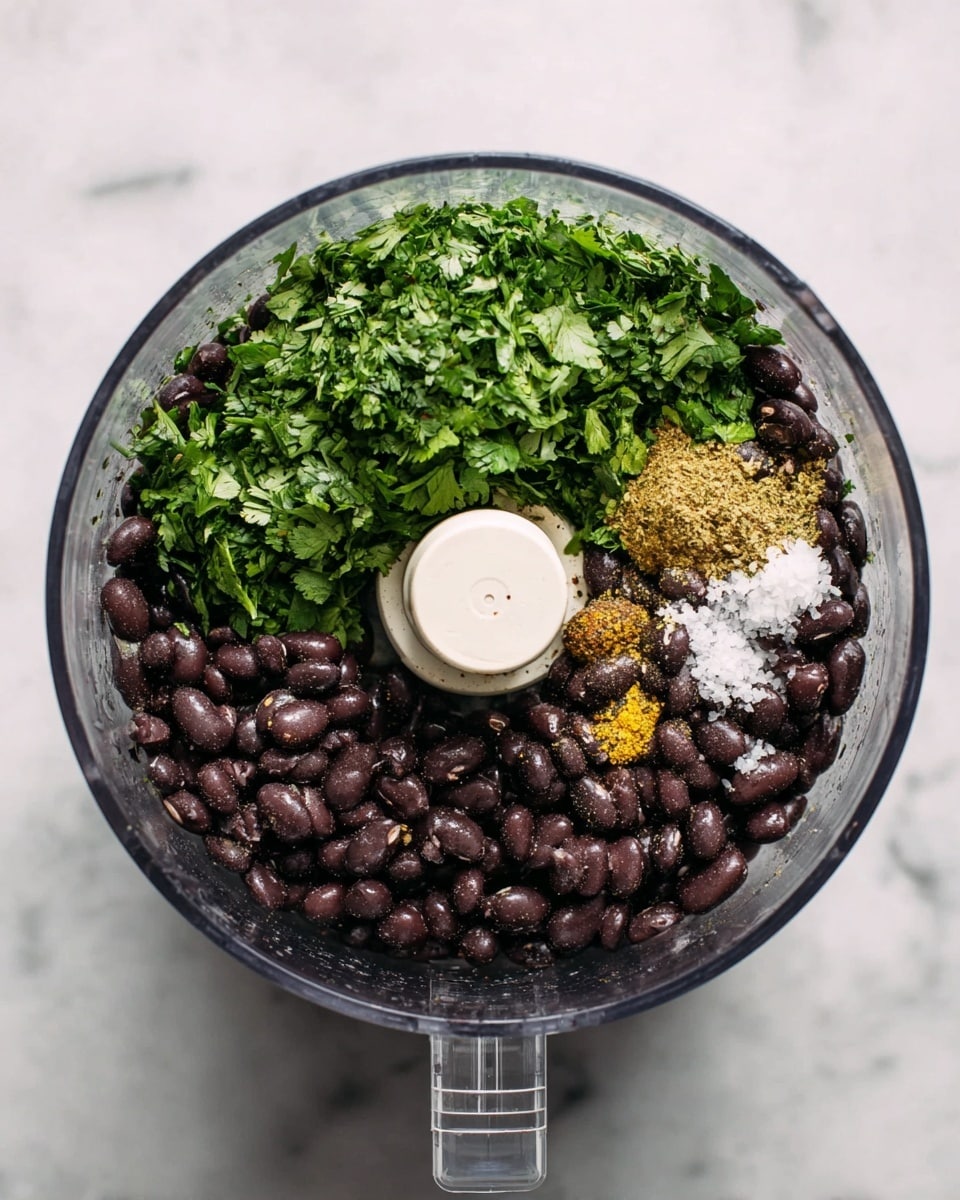 A clear food processor bowl is filled with three main layers of ingredients. The bottom layer has dark brown black beans, glossy with moisture. On the left side, there is a pile of bright green chopped cilantro with a leafy texture. On the right side, small piles of fine white salt and yellowish spices are scattered on top of the beans. The bowl rests on a white marbled surface, and the food processor’s white center blade holder is visible in the middle. photo taken with an iphone --ar 4:5 --v 7
