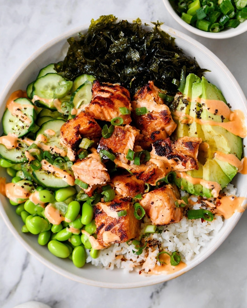 In a white bowl on a white marbled surface, there is one layer of white rice at the bottom. On top of the rice, there are several cubes of grilled salmon with a slightly charred texture, arranged in the center. Around the salmon, there are bright green edamame beans on one side, sliced green cucumber pieces with a creamy orange sauce drizzled over them on another side, and sliced avocado with the same orange sauce on top on the opposite side. A large piece of dark green seaweed is placed behind the salmon cubes. The whole dish is sprinkled with small chopped green onions and some black seasoning bits. photo taken with an iphone --ar 4:5 --v 7