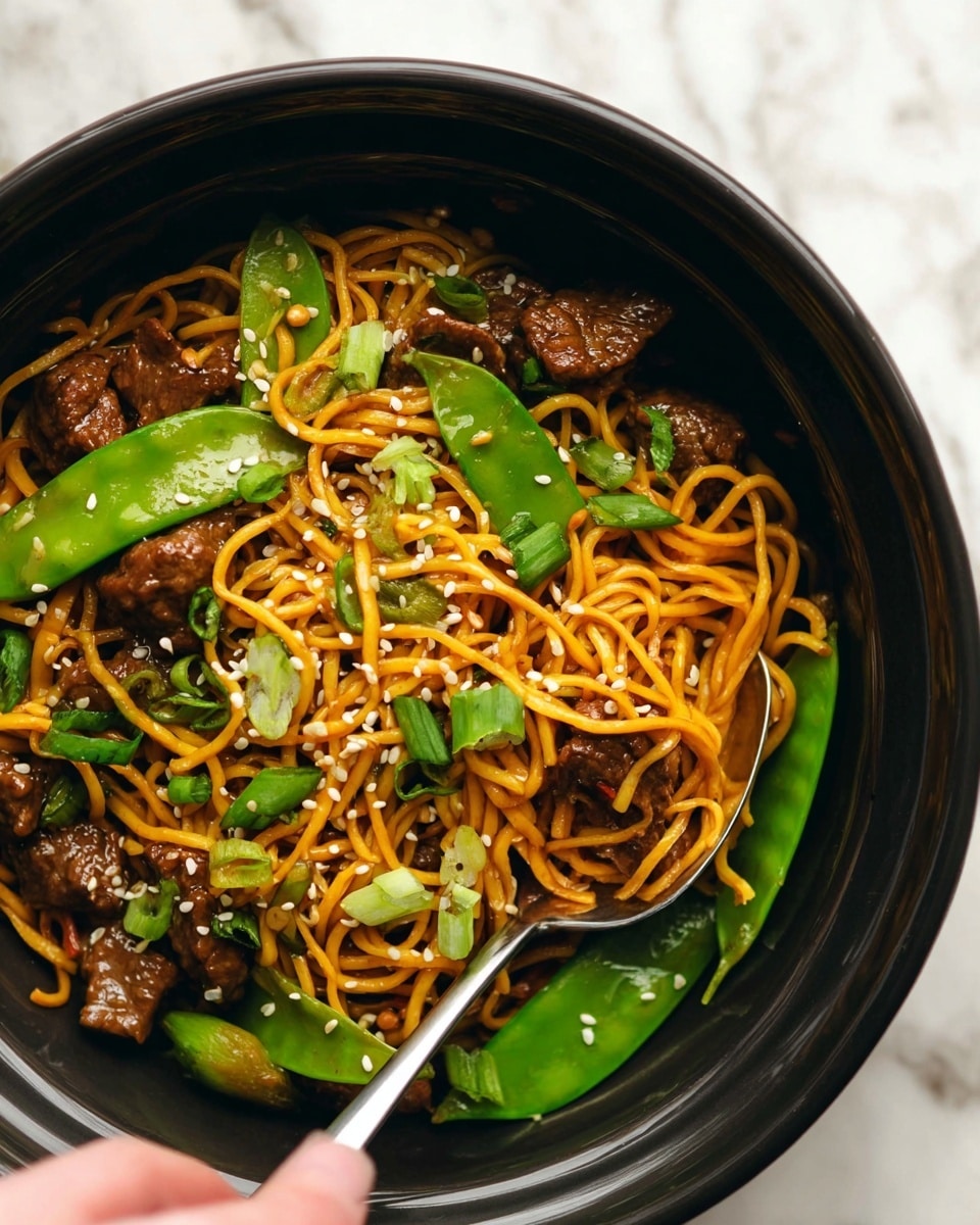 The image shows a close-up of a black bowl filled with four main layers: the bottom layer is thin, yellow-orange noodles tangled together; scattered throughout the noodles are medium brown, glossy chunks of meat; bright green snap peas and some chopped green onions sit mixed in with the noodles and meat, adding fresh color; white sesame seeds are sprinkled over the top, adding texture and detail. A silver spoon is partially buried in the noodles near the bottom right side of the bowl, held by a woman's hand. The bowl is placed on a white marbled surface. Photo taken with an iphone --ar 4:5 --v 7