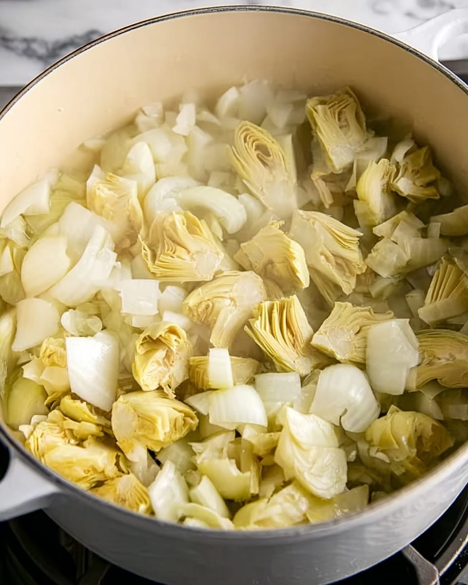 A white pot filled with chopped white onions forming the bottom layer, topped with broken artichoke pieces in pale yellow and light green shades scattered evenly over the onions. The pot sits on a stove with a black edge visible around it. The background shows a white marbled texture. The lighting highlights the glossy texture of the cooked onions and artichokes steam gently rising. Photo taken with an iphone --ar 4:5 --v 7