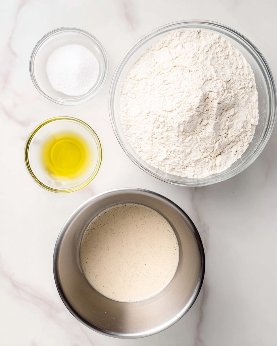 The image shows four bowls with different ingredients placed neatly on a white marbled surface. The largest bowl, a shiny silver mixing bowl in the bottom center, contains a foamy, beige liquid that fills the base. Above it to the right is a large clear glass bowl filled with fine, white flour that has a slightly uneven surface texture. To the left of the flour bowl, there are two smaller clear glass bowls: the top one contains white granulated salt, and the bottom one holds a small amount of yellow oil with a smooth, reflective surface. The bowls form an organized layout over the white marbled background. Photo taken with an iphone --ar 4:5 --v 7