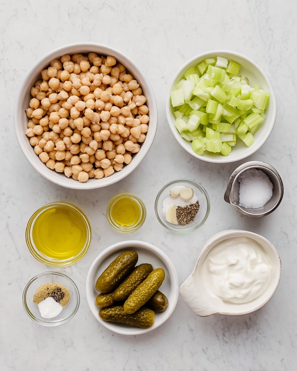 The image shows a top-down view of seven small containers placed on a white marbled surface. The largest, a white bowl on the left, is filled with light brown chickpeas. To its right, there is a white bowl with chopped pale green celery. Below that is a smaller white dish holding three whole pickles and two garlic cloves. Above these, in small clear bowls, are light yellow lemon juice, golden olive oil, black ground pepper, coarse sea salt, and a small metal cup filled with white creamy yogurt. All the containers are neatly arranged and evenly spaced. Photo taken with an iphone --ar 4:5 --v 7