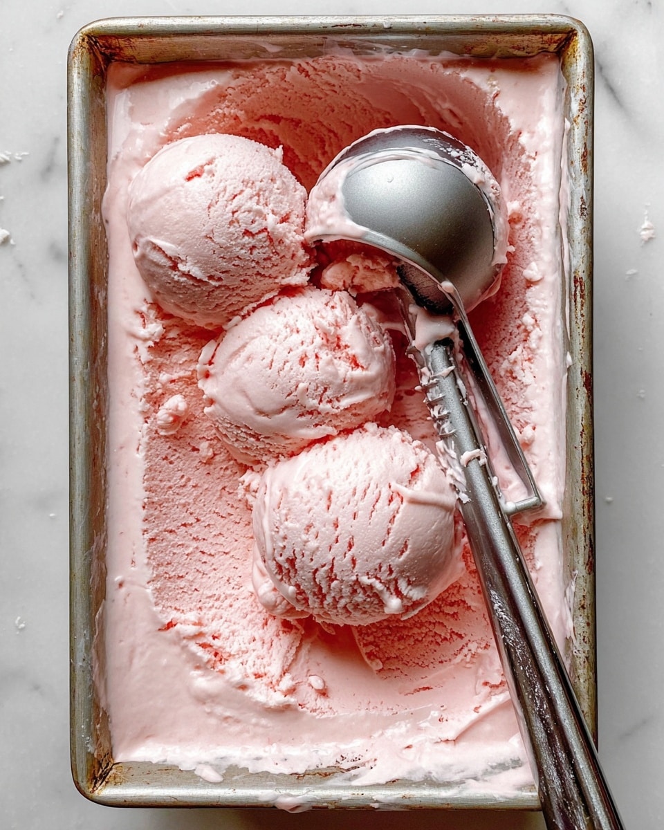 A close-up top view of a rectangular metal pan filled with smooth and creamy pale pink ice cream, with three rounded scoops taken out and placed in the pan, showing soft texture and slight swirls on each scoop. A shiny silver ice cream scoop rests in the ice cream, partly covered with the pink ice cream. The pan edges are slightly old and worn, with some ice cream spilled around the sides. The pan is placed on a white marbled surface. Photo taken with an iphone --ar 4:5 --v 7