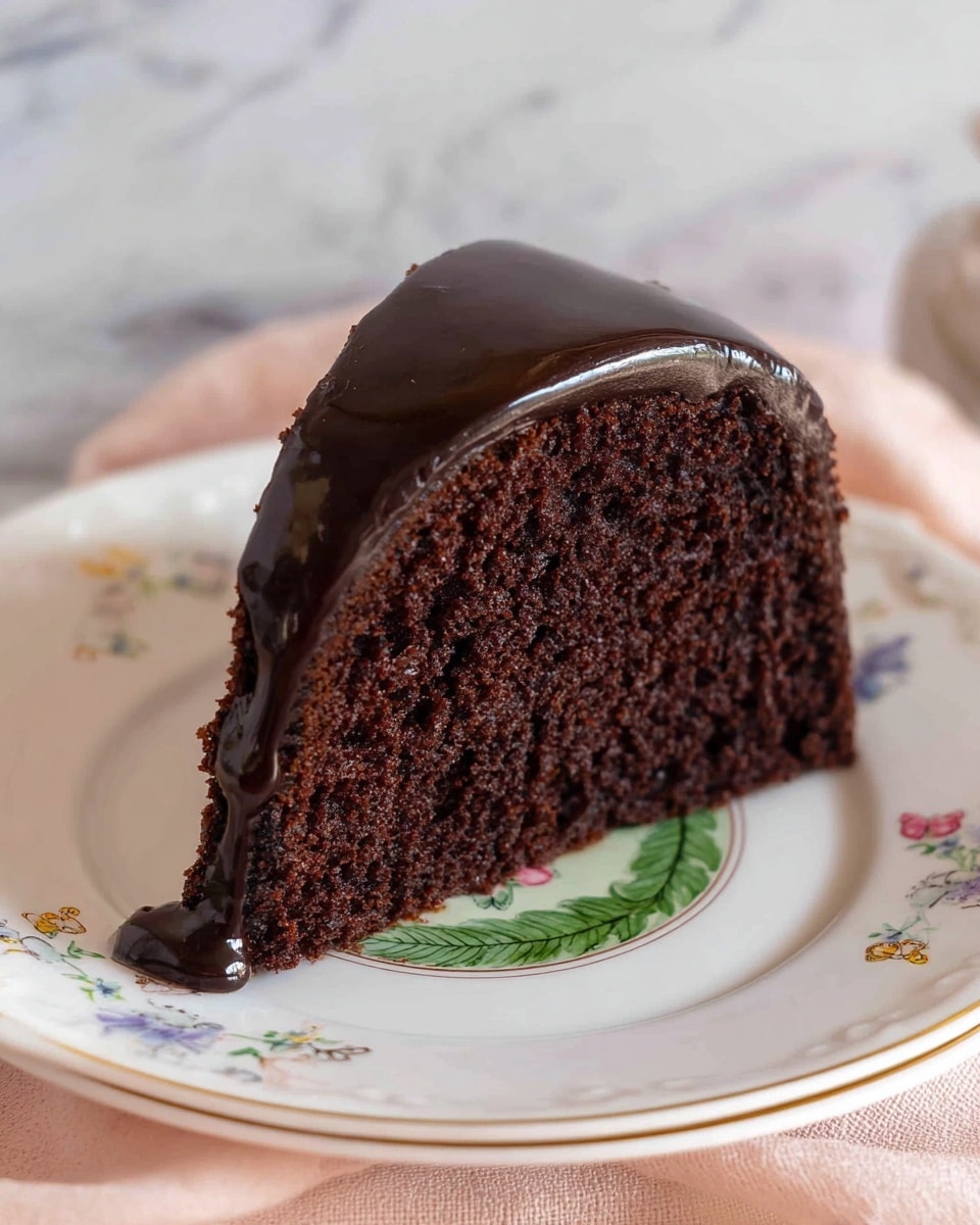 A rich, dark chocolate bundt cake sits on a clear glass cake stand with intricate patterns. The cake has one slice removed, showing a soft, dense interior that is almost black in color. The thick chocolate glaze covers the top and flows down the sides unevenly, creating shiny drips that glisten under the light. The background is a white marbled texture that adds a clean and simple feel to the image. photo taken with an iphone --ar 4:5 --v 7