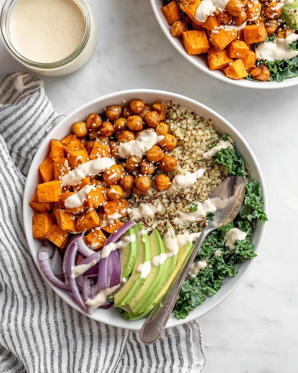 The image shows a white bowl filled with several layers of colorful food. At the bottom is a light brown and white mix of quinoa grains. On one side, there are bright orange roasted cubes of sweet potatoes, and next to them is a pile of golden brown roasted chickpeas with sesame seeds sprinkled on top. Beside the chickpeas, there are slices of light green avocado, and below it, dark green kale leaves. At the bottom left are soft cooked purple onion slices. The bowl is drizzled with a creamy white sauce. A silver spoon rests inside the bowl on the right side. The bowl sits on a white marbled surface next to another similar bowl and a small white jar of sauce on the left. There is a white and black striped cloth next to the sauce jar photo taken with an iphone --ar 4:5 --v 7