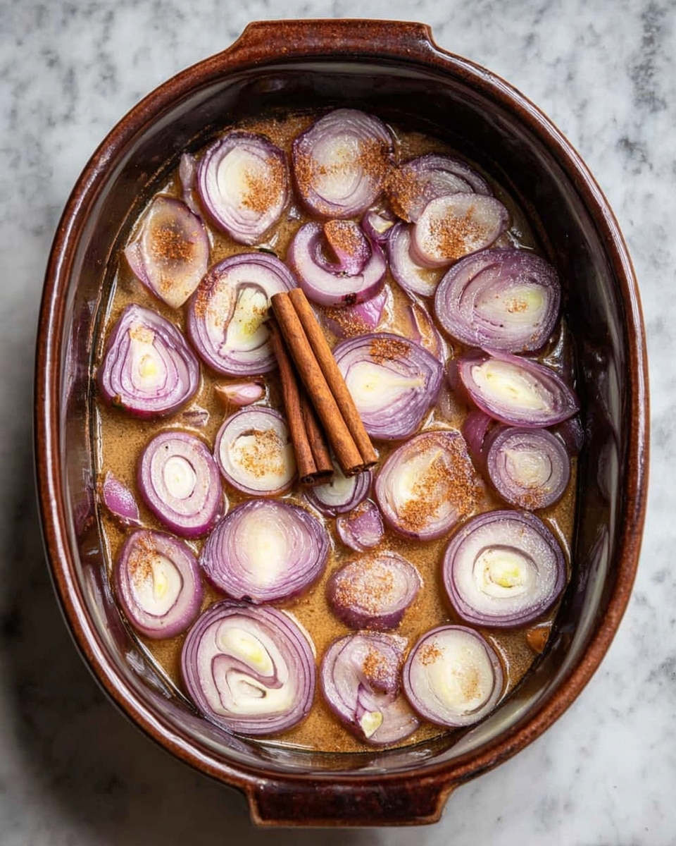 A dark brown baked dish filled with a liquid layer of light brown color, topped with evenly spread slices of light purple and white onions showing their spiral textures, some slices cut in halves and quarters. Two cinnamon sticks are placed near the center, standing out with their deep brown color and rough texture. This dish sits on a white marbled surface. photo taken with an iphone --ar 4:5 --v 7