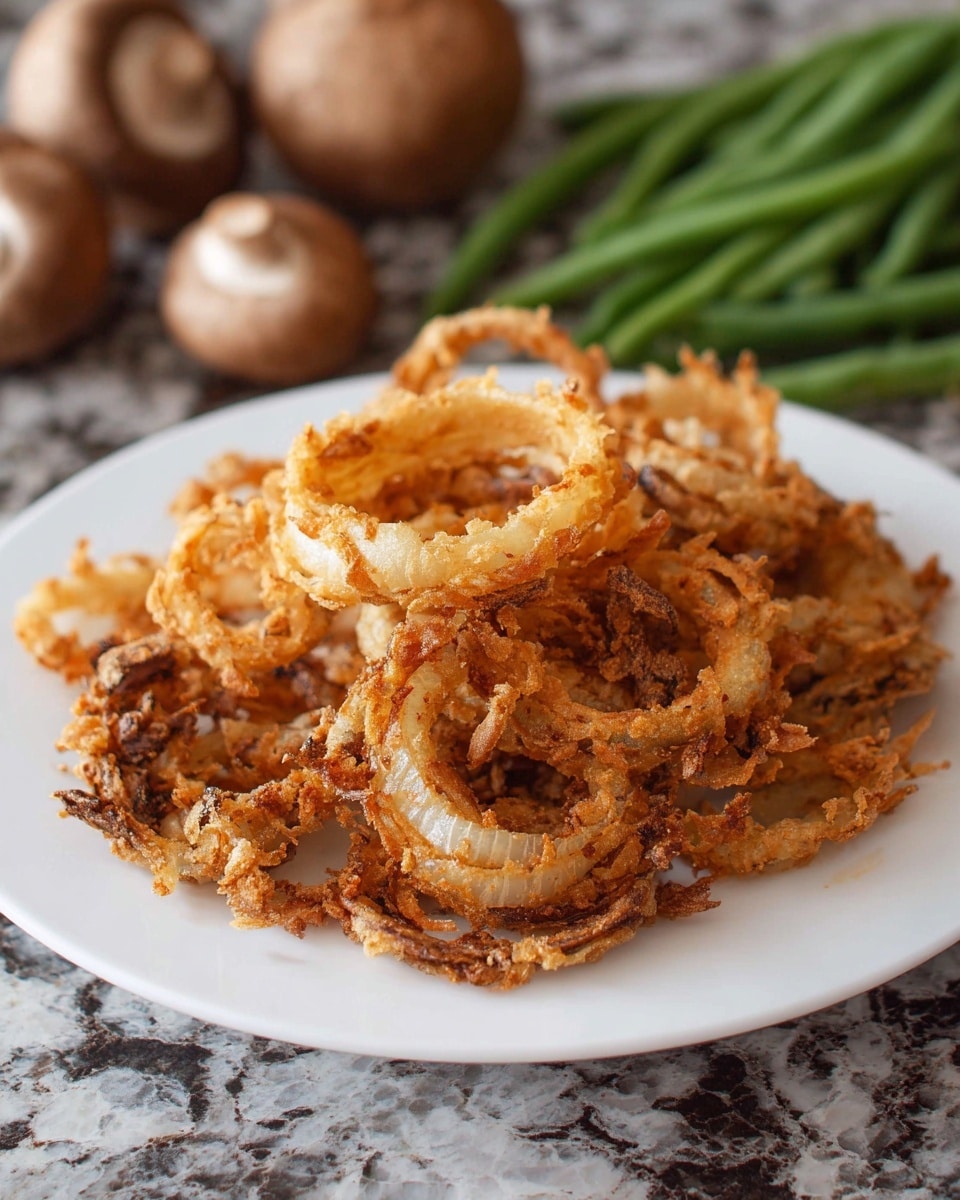 A white plate holds a heap of crispy fried onion rings that are golden brown with some darker edges, showing a crunchy texture. The rings are uneven in size and stacked loosely in the center of the plate. The background shows green beans and whole brown mushrooms slightly out of focus on a white marbled surface. Photo taken with an iphone --ar 4:5 --v 7