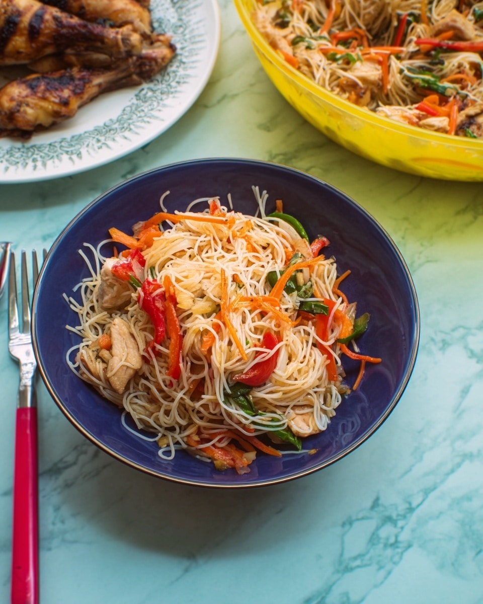 A blue bowl filled with thin white rice noodles mixed with bright orange carrot strips, green leafy vegetables, red bell pepper strips, and small beige tofu pieces, all mixed together with a light sauce giving a slightly glossy texture. Behind the bowl on the left, a white plate holds sliced golden-brown roasted pieces of chicken. On the right, a large transparent bowl contains more of the noodle salad. A fork with a red handle lies on the white marbled surface next to the blue bowl. The setting is clean and colorful, with the food looking fresh and inviting. photo taken with an iphone --ar 4:5 --v 7
