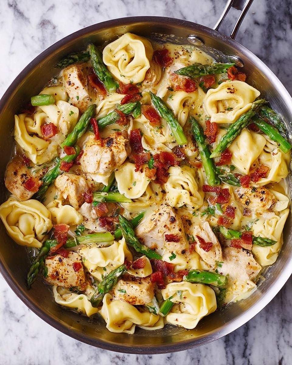 A metal pan filled with a creamy pasta dish featuring two main layers: the first layer contains light yellow tortellini pasta with a smooth texture, and the second layer has bright green asparagus spears sliced in half and tender-looking pieces of seasoned chicken. Small bits of crispy reddish-brown bacon are scattered evenly across the dish. The sauce appears glossy and coats the pasta and other ingredients evenly. The pan is set on a white marbled surface. Photo taken with an iphone --ar 4:5 --v 7