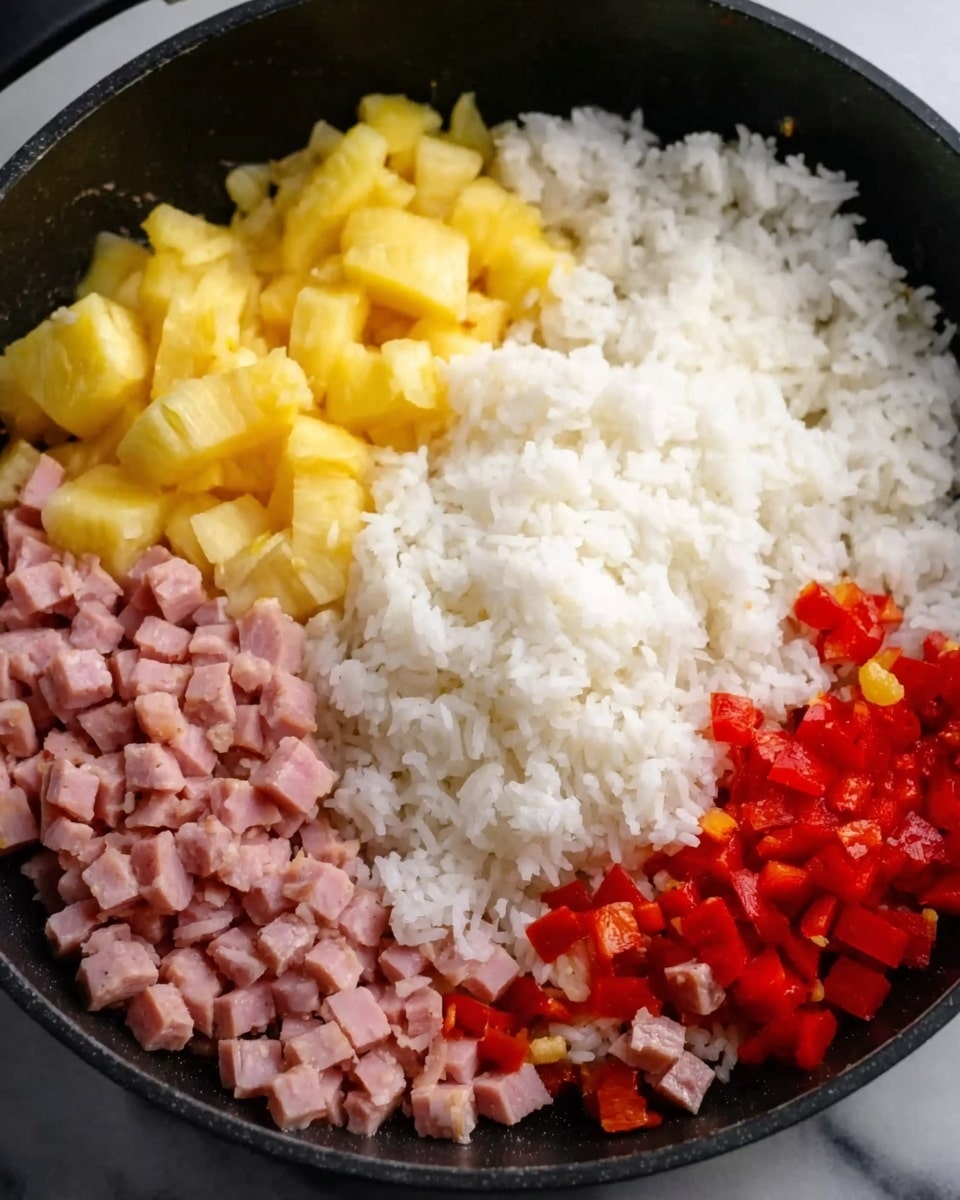 A close-up of a black pan filled with four main ingredients neatly placed in separate sections: at the top left, bright yellow pineapple chunks; at the top right, a mound of white cooked rice; at the bottom left, small pieces of red bell pepper; and at the bottom center-left, diced pink ham. The pan sits on a white marbled surface. photo taken with an iphone --ar 4:5 --v 7