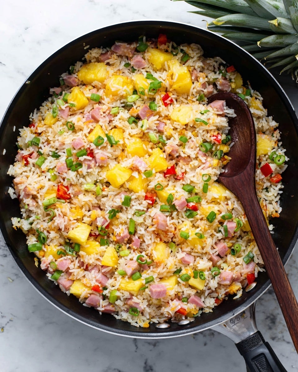 A black pan filled with a colorful mix of fried rice, showing three main layers: the base layer of white rice with a slightly golden tint from cooking, a middle layer mixed evenly with bright yellow pineapple chunks and small pink cubes of ham, and a top layer scattered with green onion slices and red bell pepper pieces. A dark wooden spoon is partially placed into the pan from the right side, stirring the rice. The pan is placed on a white marbled surface with a bit of green pineapple leaves visible in the upper right corner. photo taken with an iphone --ar 4:5 --v 7