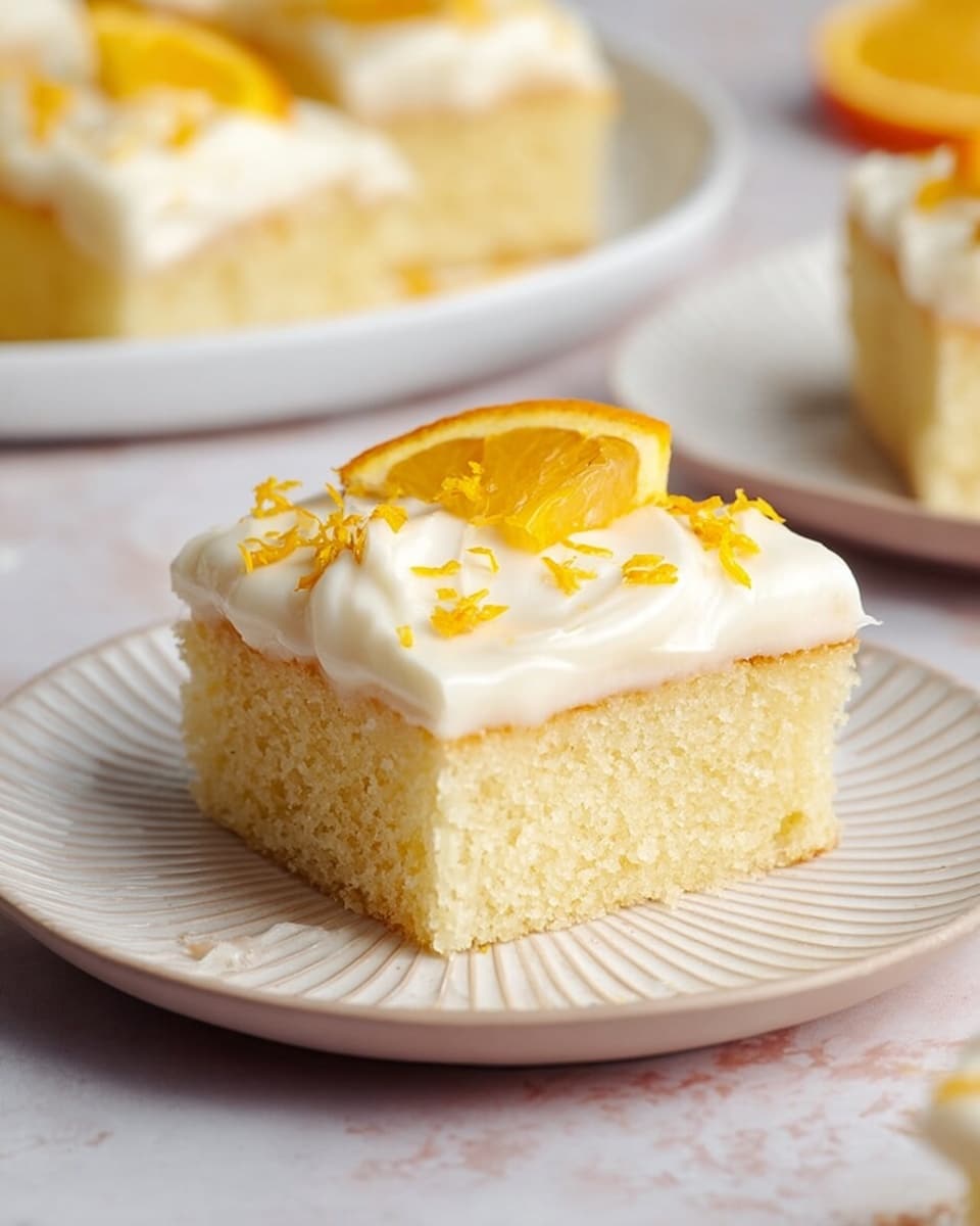A single piece of soft, light yellow cake sits on a white plate with a ridged edge. The cake is frosted with a thick, smooth white cream layer on top. Small orange zest pieces are sprinkled over the frosting, and a small slice of orange wedge is placed on top as decoration. In the soft-focus background on a white plate, there are more pieces of the same cake with similar frosting and orange garnish. The items rest on a white marbled surface. photo taken with an iphone --ar 4:5 --v 7