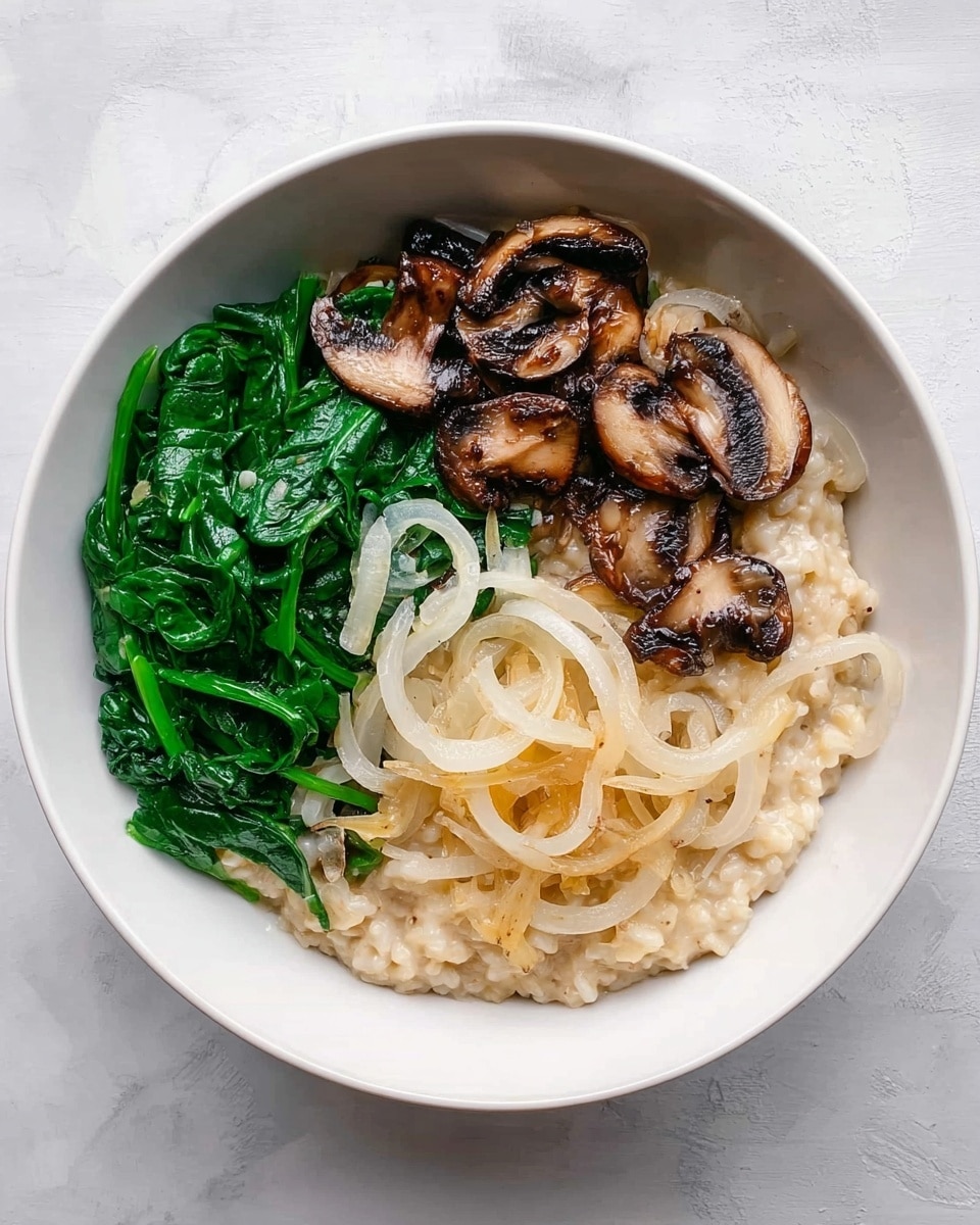 In a white bowl on a white marbled surface, there is a dish with three main parts arranged side by side. On the left side, there is a pile of bright green cooked spinach with a glossy texture. In the middle and right parts, there is creamy beige risotto topped with thin, translucent white rings of cooked onions and some light yellow grated cheese scattered on top. Above the risotto, there are dark brown sautéed mushroom slices with a slightly shiny surface. The ingredients are neatly placed without mixing, showing clear layers of spinach, mushrooms, and risotto with onions and cheese. Photo taken with an iphone --ar 4:5 --v 7