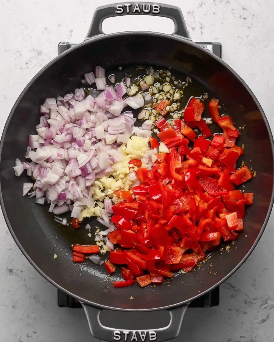 The first part of the image shows a dark gray pan with diced light purple onions on the left side and sliced bright red bell peppers on the right side, all resting in some oil. The second part of the image shows the same pan where some onions have turned translucent, the red peppers are softer, and in the center, small pale yellow and white minced pieces, likely garlic and ginger, have been added. The pan has two handles labeled