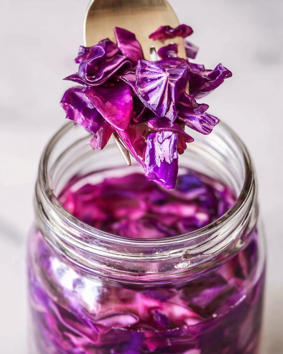 A close-up view of a clear glass jar filled with bright purple shredded cabbage submerged in liquid. Above the jar, a fork with a wooden texture holds several pieces of the same vibrant purple cabbage, showing detailed layers and slight translucence. The background is a white marbled texture, creating a clean and simple look. photo taken with an iphone --ar 4:5 --v 7