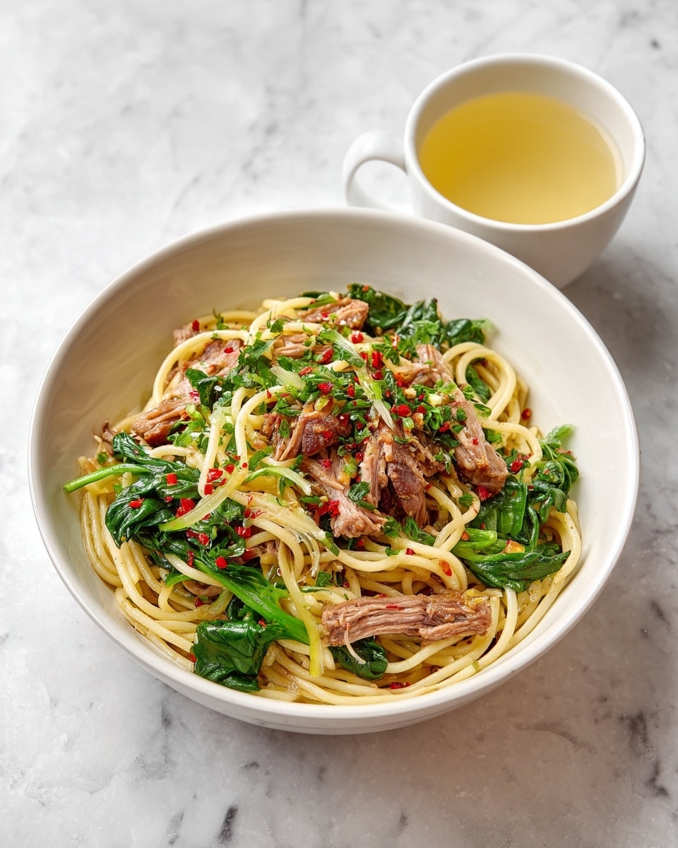 A white bowl filled with spaghetti pasta mixed with shredded cooked meat and fresh green leafy vegetables, sprinkled with finely chopped herbs and small red chili flakes. The pasta strands are light yellow, soft, and twisted around the meat pieces, which are brown and tender. The green leaves add brightness and freshness, scattered evenly throughout the dish. Next to the bowl is a small white cup containing a light yellow liquid. All is placed on a white marbled surface. photo taken with an iphone --ar 4:5 --v 7