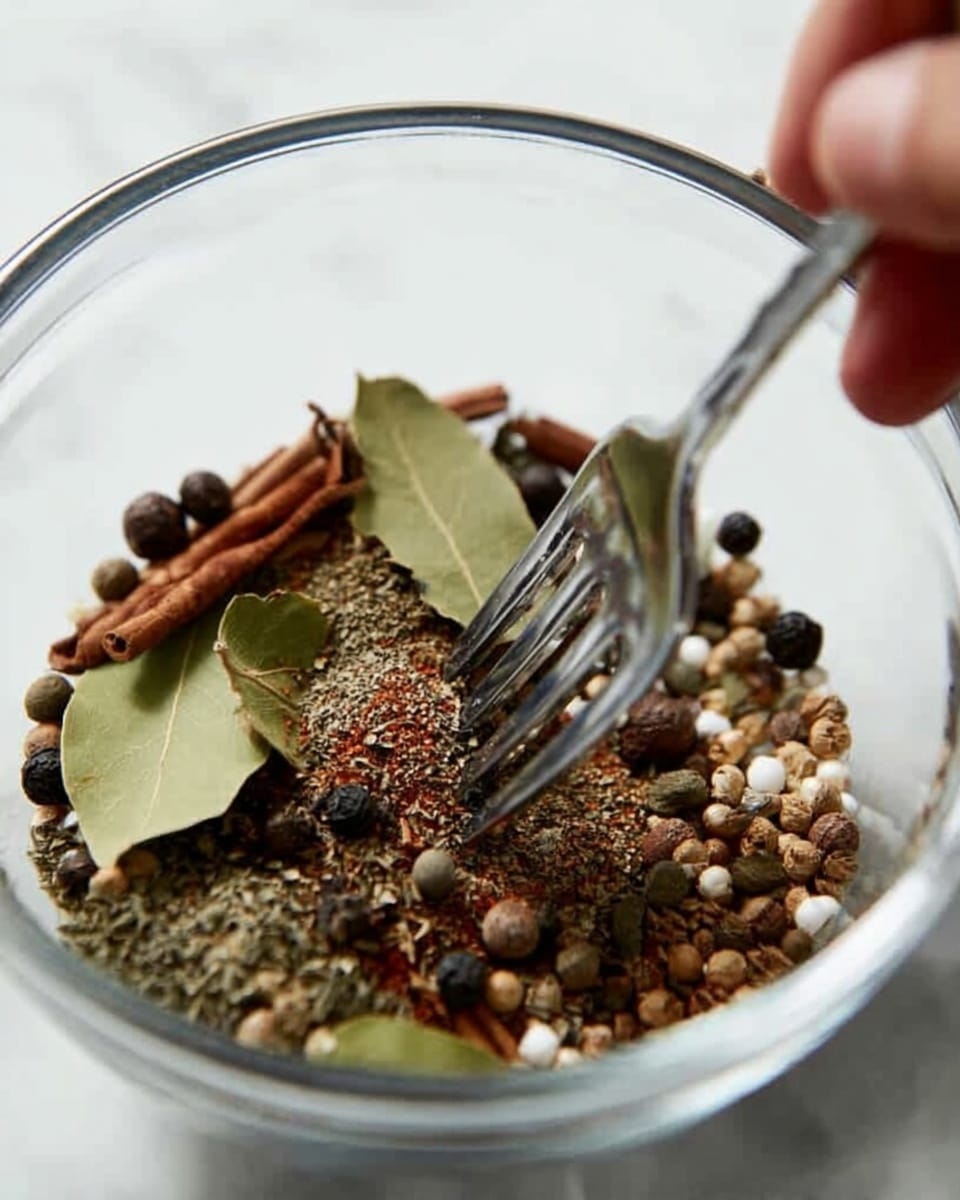 A clear glass bowl sits on a white marbled surface, filled with a mixture of spices including brown cinnamon sticks, green bay leaves, black and white peppercorns, and small round mustard seeds. A woman's hand holds a fork that is stirring or picking through the spices, the metal fork positioned vertically in the bowl. The spices have varied textures, from smooth round peppercorns to rough dried leaves, creating a rich visual contrast. Photo taken with an iphone --ar 4:5 --v 7