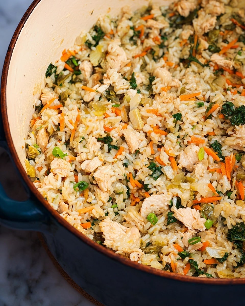 This image shows a close-up of a large white pot filled with a mixed dish of cooked rice with small pieces of light brown cooked chicken, chopped green leafy vegetables, and thin orange carrot strips scattered throughout. The rice appears fluffy and mixed evenly with the other ingredients, giving a textured look with varied colors from soft beige to green and bright orange. The inner wall of the pot is white, and the outside edge of the pot visible is a dark glossy blue. The whole pot rests on a white marbled surface. photo taken with an iphone --ar 4:5 --v 7