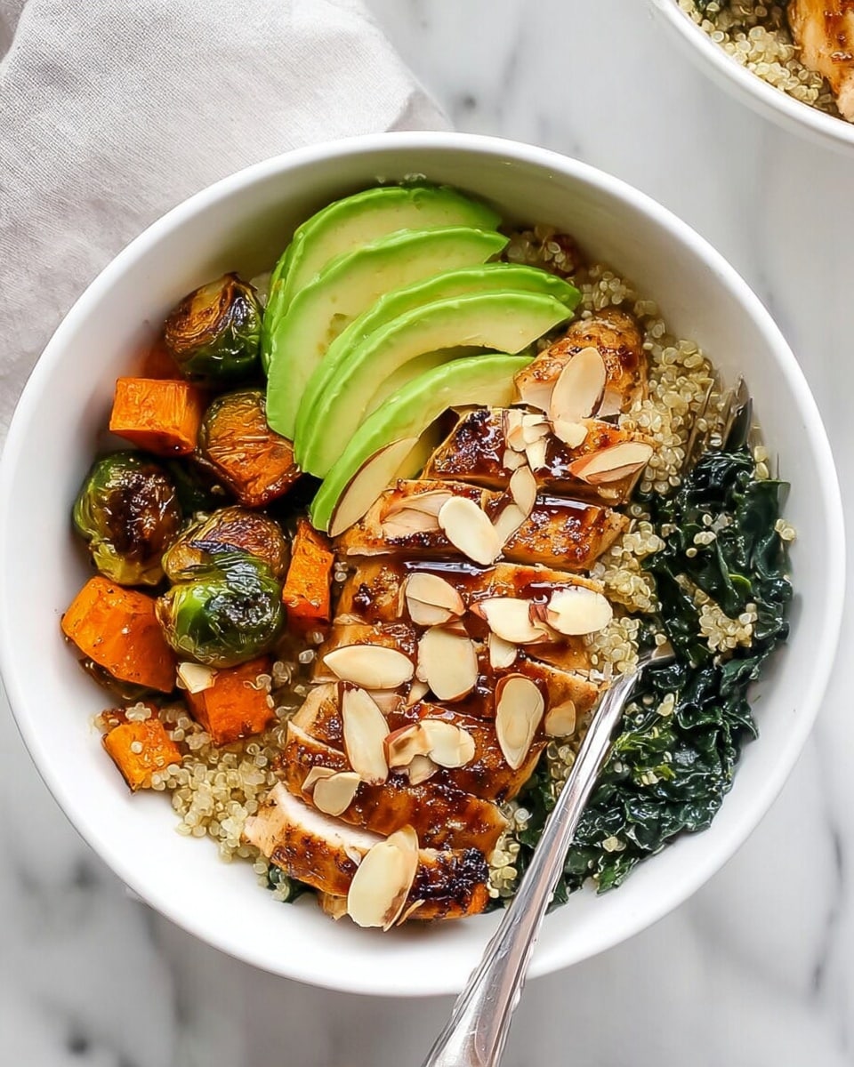 The dish is served in a white bowl placed on a white marbled surface. It has four main layers: on the bottom, a bed of dark green kale leaves until the sides of the bowl; next, roasted light orange sweet potato cubes and light green Brussels sprout halves mixed together; then, slices of pale green avocado arranged on one side; on top, golden brown grilled chicken with charred marks, sliced and laid out in a row. The dish is topped with toasted almond slices spread evenly over everything. A silver spoon rests inside the bowl. Photo taken with an iphone --ar 4:5 --v 7