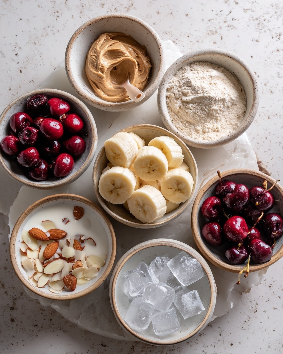The image shows several small white bowls arranged on a white marbled surface, each bowl containing different ingredients. In the center, a bowl holds evenly sliced banana pieces with a soft yellow color and light brown spots. Surrounding it are bowls filled with light brown almond butter with a smooth texture, pale beige protein powder with a scoop on top, white creamy yogurt, deep red whole cherries, dark red pitted cherries with stems, thinly sliced almond slivers, and clear ice cubes in a white bowl. The bowls have a rustic, earthy look with beige rims. photo taken with an iphone --ar 4:5 --v 7