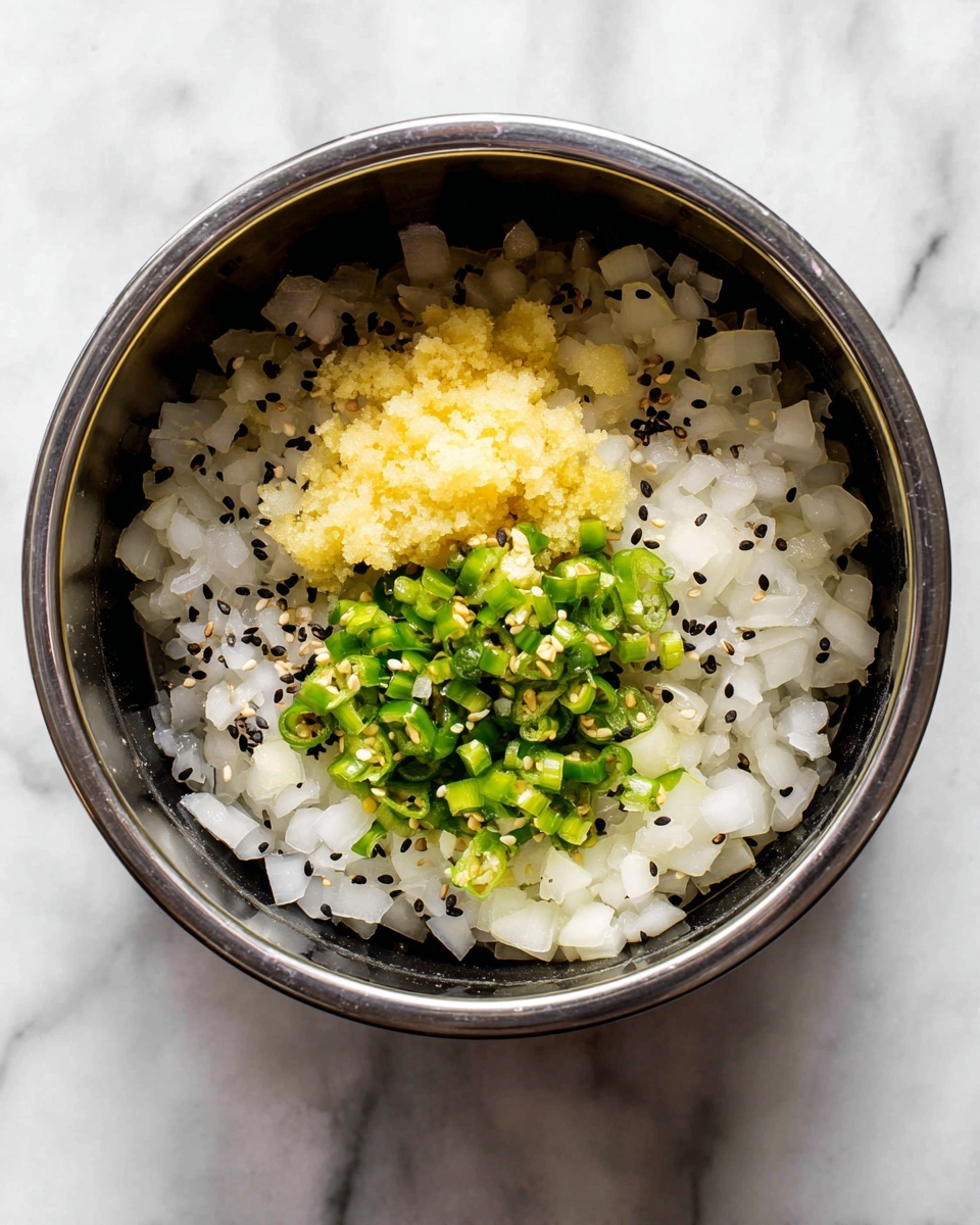 Inside a metal pot of a black electric cooker, there is a base layer of chopped white onions mixed with small black seeds, scattered evenly around the pot's bottom. On top, there is a small pile of finely minced ginger in a pale yellow color, slightly grainy in texture, and beside it, a small amount of chopped green chilies with visible white seeds, creating a contrast in the center. The pot sits on a white marbled surface with light grey and white tones around it. Photo taken with an iphone --ar 4:5 --v 7