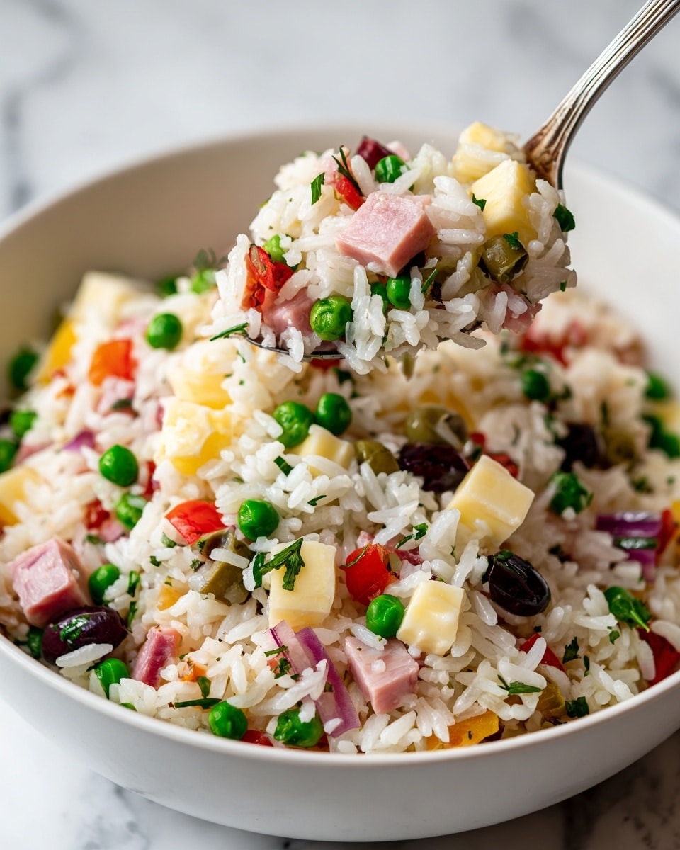 A close-up view of a white bowl filled with a mixed rice salad shows four main layers. The bottom layer is made of white rice, soft and fluffy with a slightly glossy texture. Scattered on top are small cubes of pale yellow cheese, bright green peas, and chopped olives with dark green and purple hues. There are also pieces of light pink sliced ham and red bell pepper chunks adding more color. A spoon lifts a mix of these ingredients, with the white rice grains and colorful vegetables clearly visible. The bowl sits on a white marbled surface. Photo taken with an iphone --ar 4:5 --v 7
