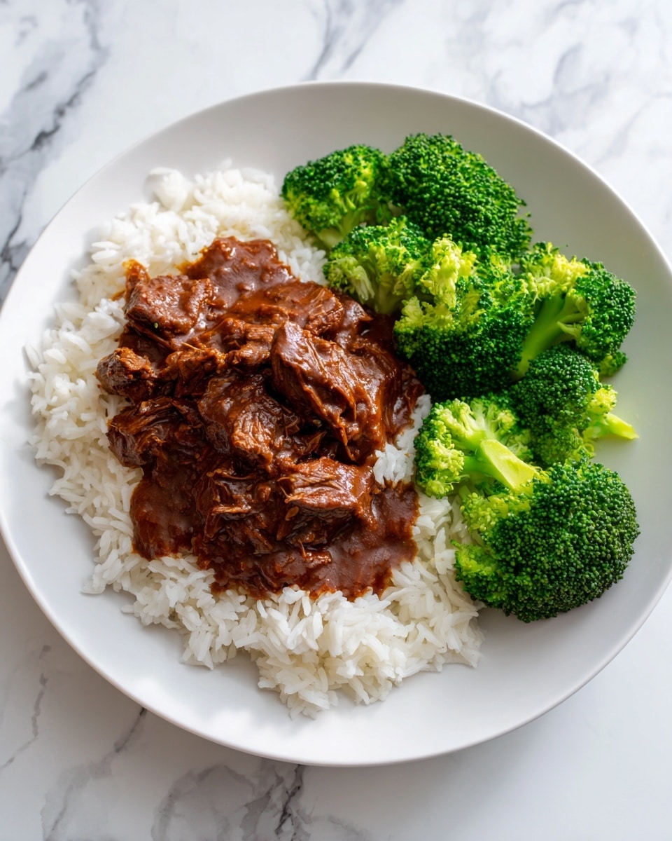 A white plate on a white marbled surface holds a meal with three main parts: at the base, a layer of white rice with visible grains covers most of the plate; on top of the rice, there is a thick, shiny brown sauce with pieces of tender cooked meat covered in the sauce, spread mostly on the left side; on the right side, several bright green broccoli florets puff up with texture and freshness, contrasting with the smooth sauce and rice. Photo taken with an iphone --ar 4:5 --v 7
