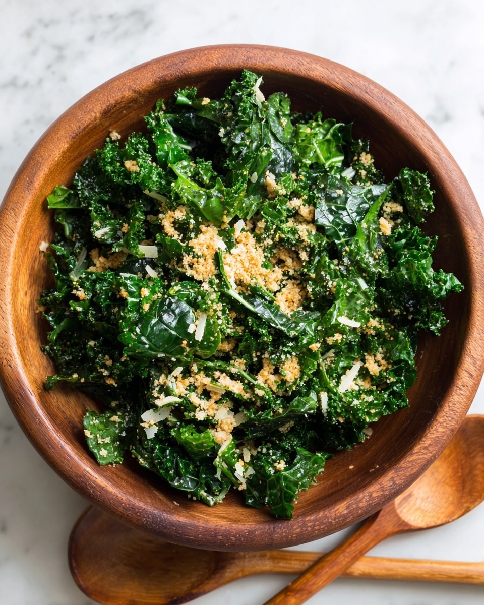 A clear glass bowl filled with fresh, dark green curly kale leaves mixed with light beige breadcrumbs and white shredded cheese scattered on top. Two light brown wooden salad forks are placed inside the bowl, partially buried in the kale. The bowl sits on a white marbled surface, and some breadcrumbs are visible around the bowl edges. Photo taken with an iphone --ar 4:5 --v 7