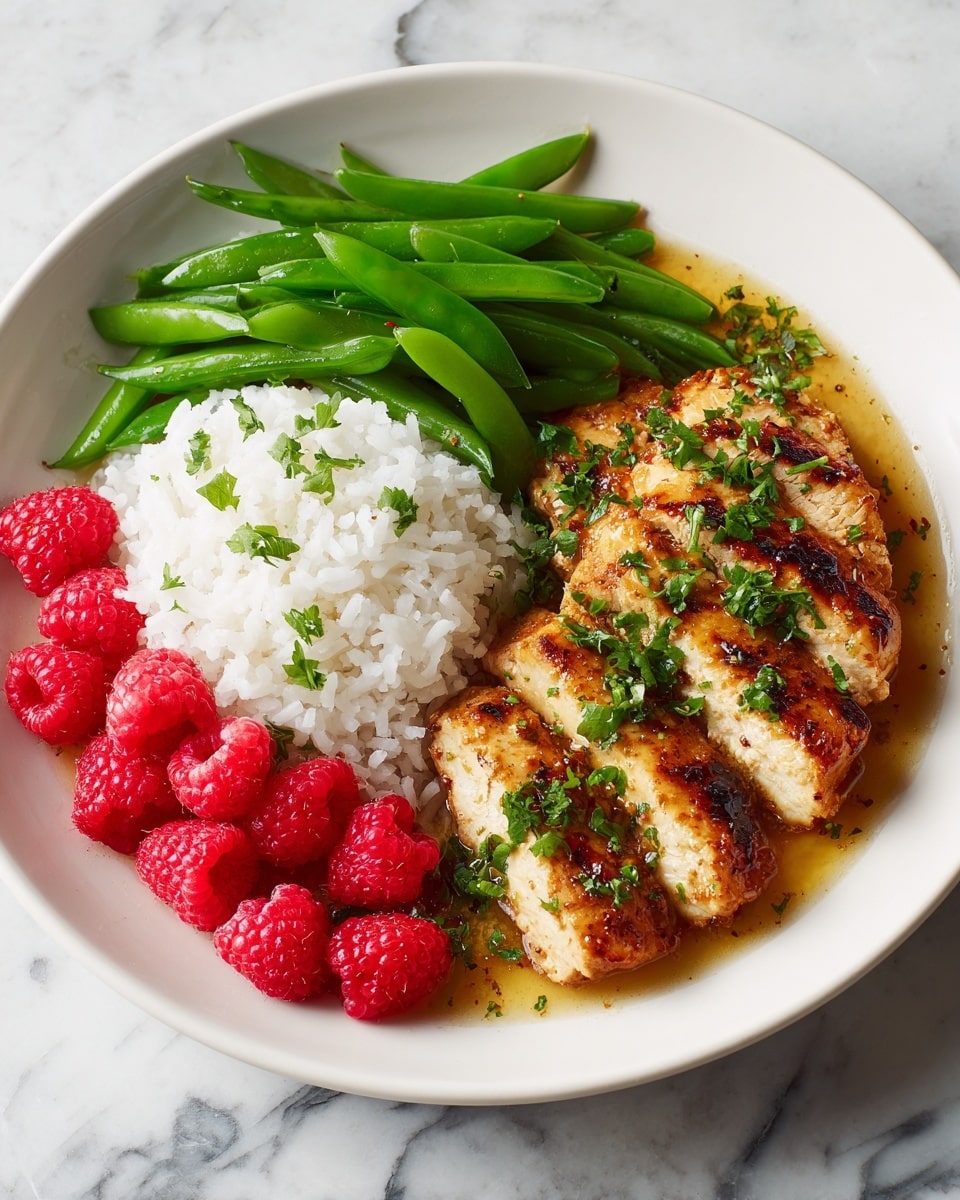 A white round plate sits on a white marbled surface. The plate holds three sections: on the bottom right is grilled chicken with a golden brown charred outside, cut into four slices with a slightly shiny and textured sauce and sprinkled with fresh green herbs. To the left of the chicken is a mound of soft white rice with fluffy grains. Above the rice are bright green cooked snap peas, cut into pieces with a smooth texture. Scattered on the plate near the bottom and center are fresh red raspberries, adding bright spots of red color. Photo taken with an iphone --ar 4:5 --v 7